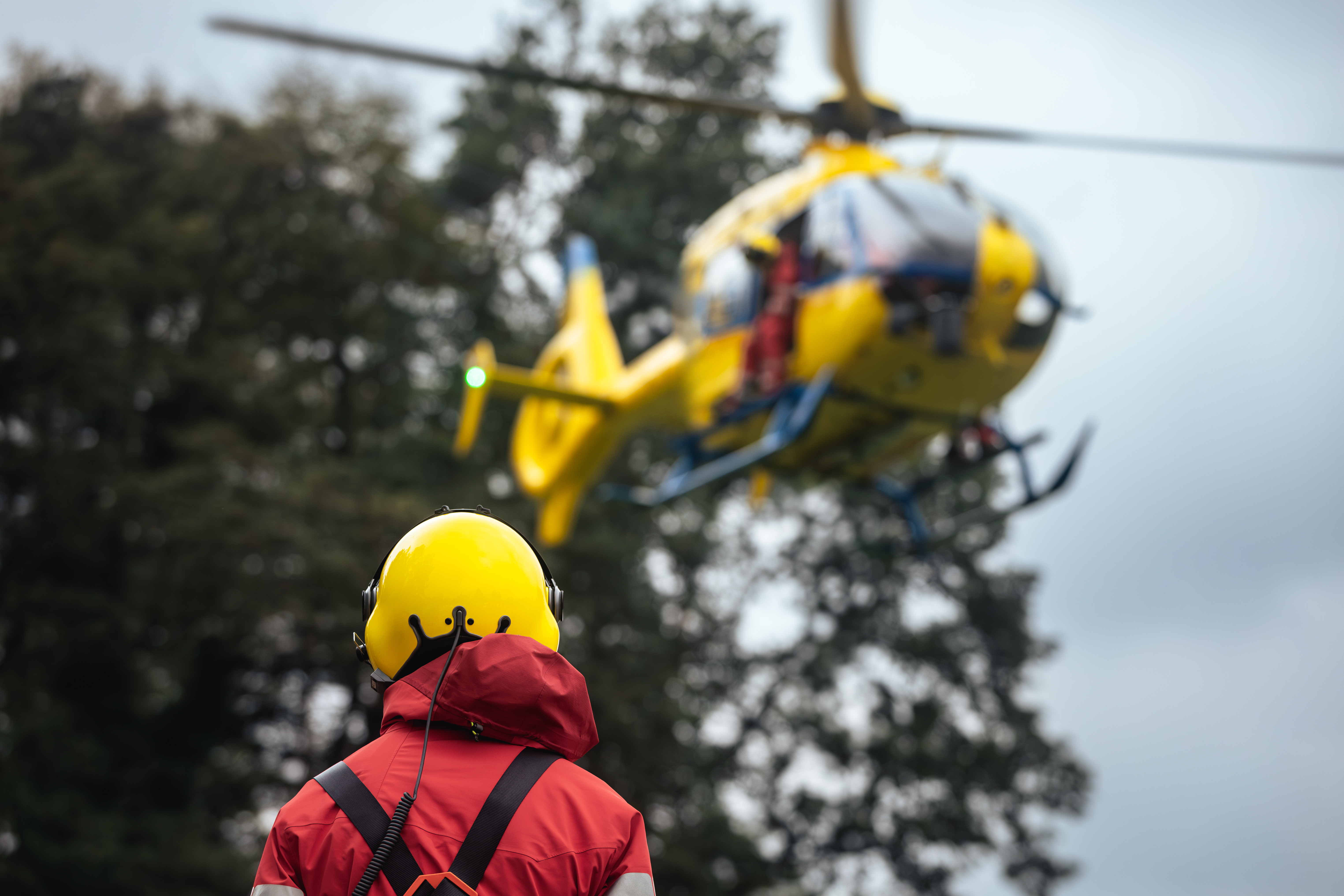 Rescue responder with comms headset maintaining situational awareness during helicopter operation